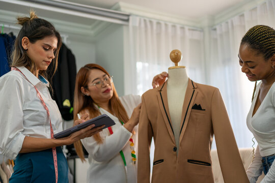 Smiling women fitting blazer on mannequin at tailor shop