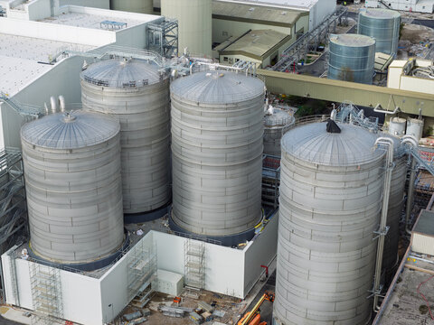 Aerial view of industrial storage tanks at a paper mill facility with metal silos and surrounding infrastructure in the United Kingdom.