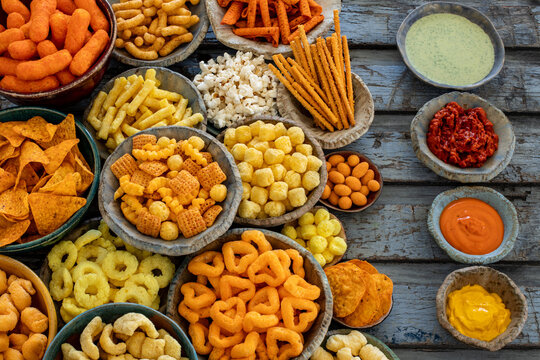 Group of salty snacks on the table, many bowls with different salty chips. 