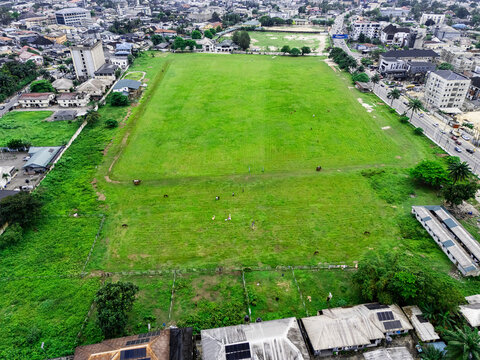 Aerial view of the Port Harcourt Polo Club featuring a large green field with horses and riders, surrounded by urban buildings and roads in Port Harcourt, Rivers, Nigeria.