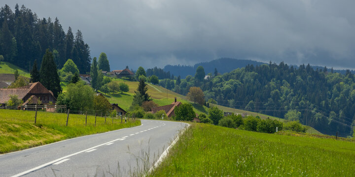 Rural road winding through green hills in Switzerland countryside
