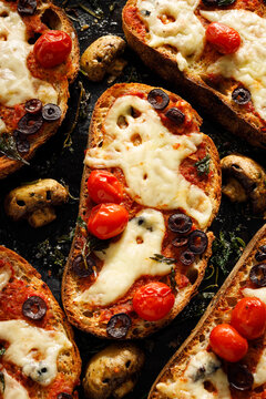 Halloween bruschetta toasts with ghost shaped melted cheese, cherry tomatoes, black olives and spooky mushrooms, top view