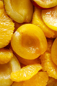 Fresh halved yellow plums with peeled orange segments, juicy fruit background close-up