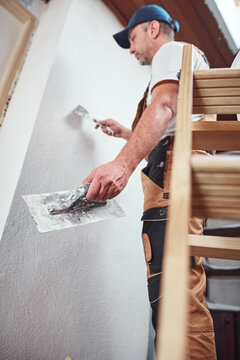 House painter putting skim coat and working on a home renovation.