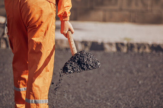 Construction worker working on a new asphalt layer on a public street.