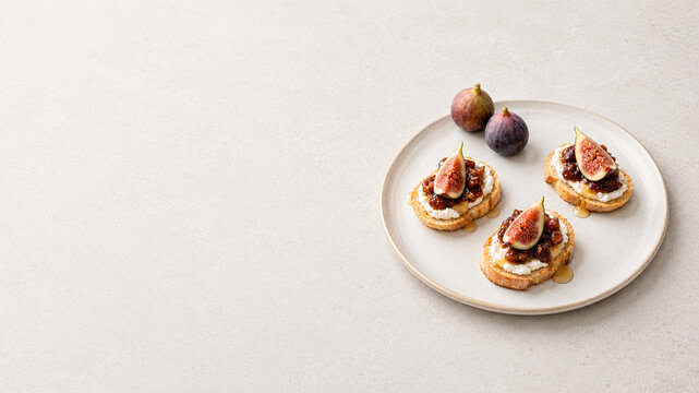 Fig toast with cream cheese, honey and fresh figs on a ceramic plate