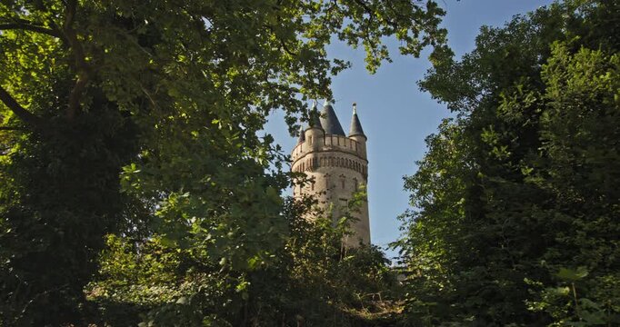 Flatow Tower partly hidden by dense summer foliage in Babelsberg Park, Potsdam, Germany.