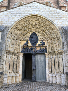 Gothic cathedral portal with carved archivolts, jamb statues, bronze tympanum and open wooden door