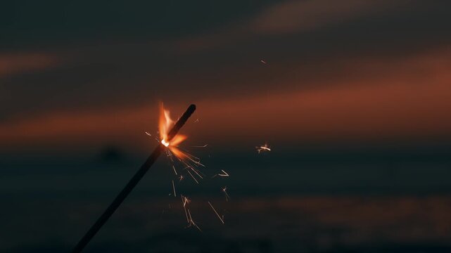 Sparkler Burning and Sparkling on Sandy Beach during Dusk at Coast