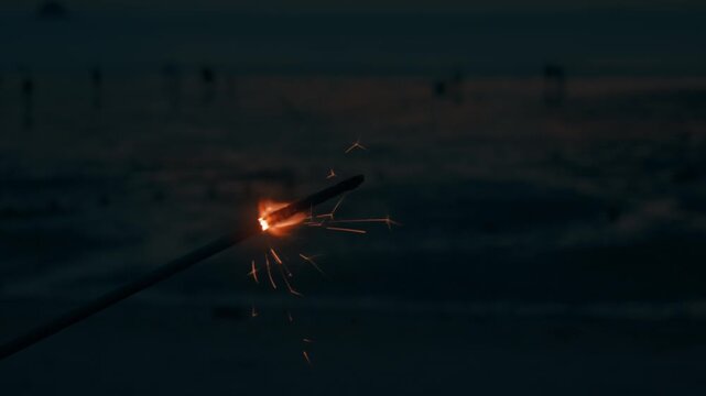 Sparkler Burning and Sparkling on Sandy Beach during Dusk at Coast