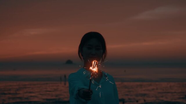 Woman Holding Sparkler Firework on Beach at Sunset during Dusk