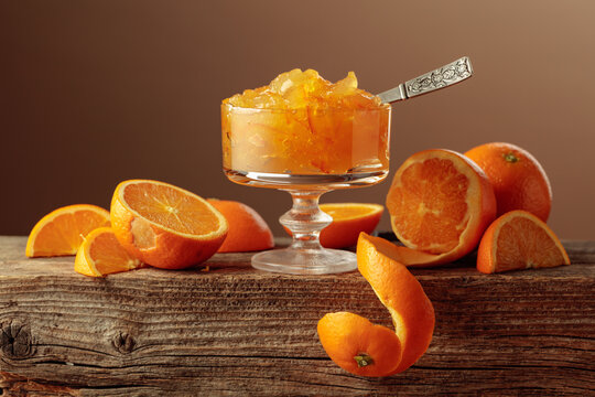 Orange marmalade in a glass dessert bowl on an old wooden table.