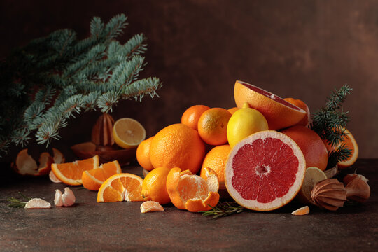 Citrus fruits and branch of spruce on a brown background.