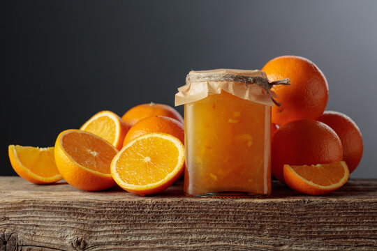 Homemade orange jam in a glass jar on on a black background.