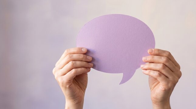 Person hands holding a blank purple paper speech bubble cutout as a symbol for communication, feedback, and social media message