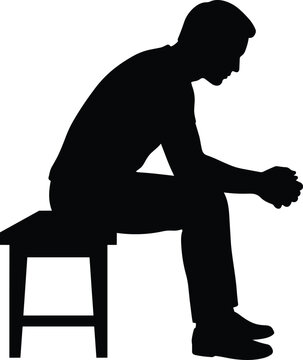 Man sitting on stool silhouette profile view with head bowed down in deep thought or sadness isolated on white