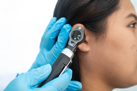 Otolaryngologist or ENT physician doctor examining senior patient ear with otoscope, hearing loss problem.