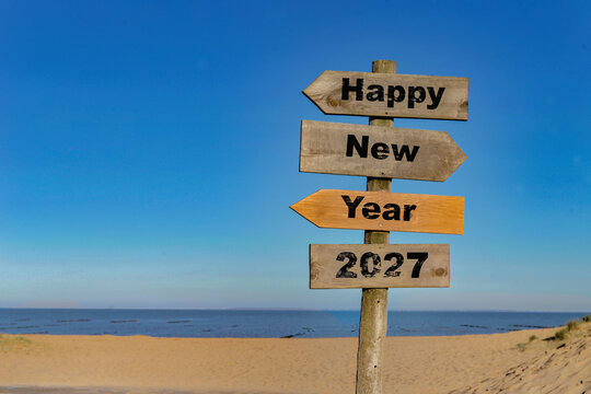 2027  happy new year written on a direction sign in front of a beach on blue sky