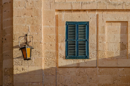 Green Wooden Window Shutter on Sandstone Wall with Vintage Lantern