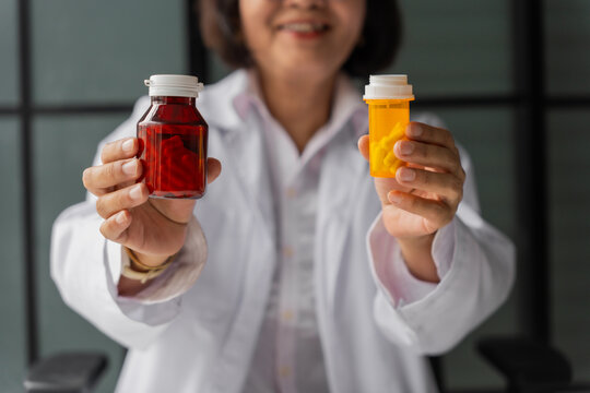 Mature Asian pharmacist show two medicine bottle