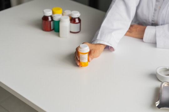Mature Asian pharmacist show medicine bottle on table