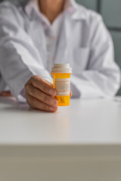 Mature Asian pharmacist show medicine bottle on table