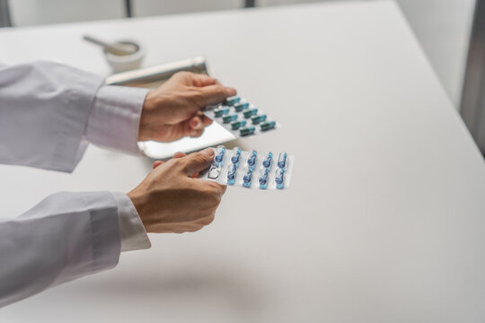  Mature Asian pharmacist holding medicine by hands