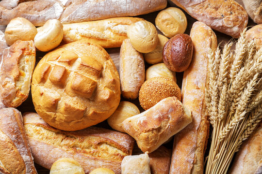fresh baked bread and wheat ears as background, top view