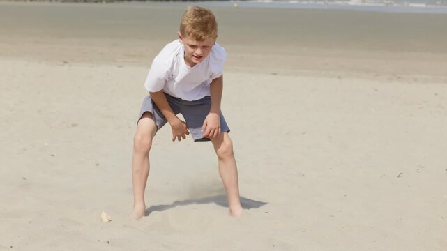 Barefoot boy digging in the sand on a sunny beach active beach vacation