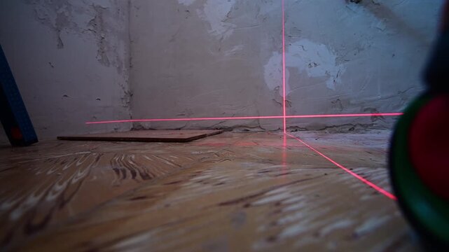 Construction worker using a laser level on a wooden floor