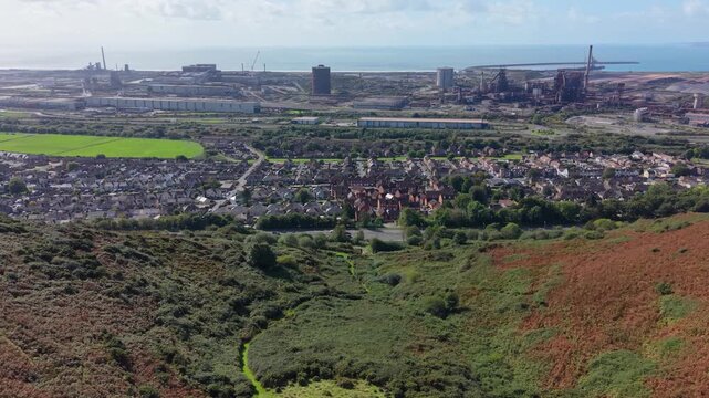 Sideways Aerial of Port Talbot Steelworks Seen from Coastal Path with M4 Motorway and Rows of Terraced Housing.