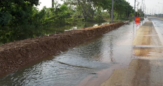 Dirt barrier holding back high water level beside asphalt road
