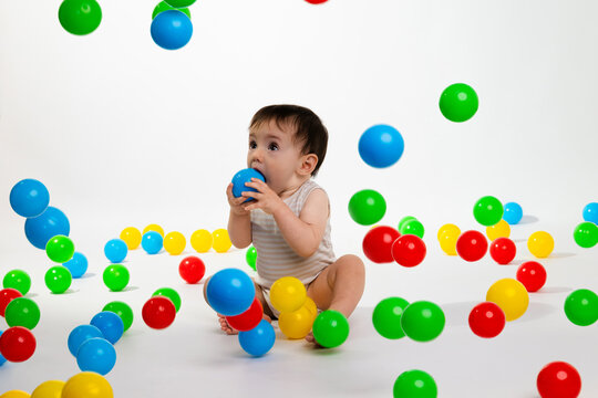 Baby playing with colorful plastic balls in studio