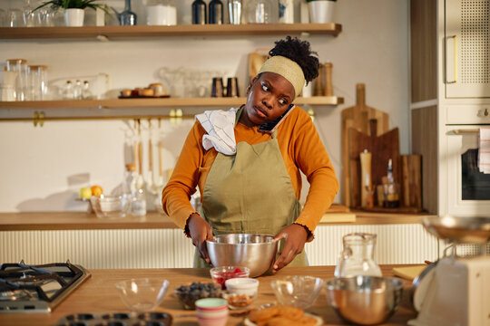 Woman baking while talking on the phone in a home kitchen