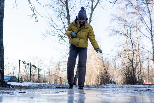 woman walks cautiously along an icy street on a winter day. Boots standing on icy, slippery ground, showing danger of winter ice and the risk of slipping on a frozen surface.