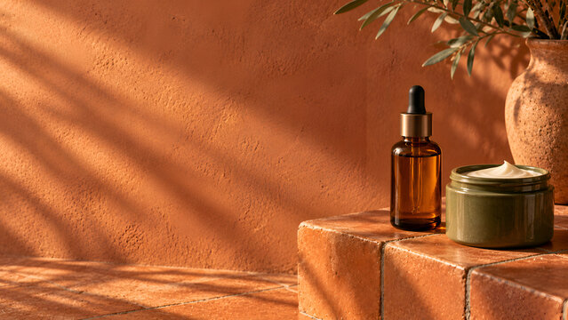 Orange terracotta tile skincare campaign banner with amber dropper and green cream jar