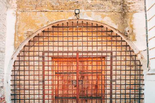 Metal iron grid barrier protecting a historical arched entrance. Concept of maximum security, architectural heritage and fortress protection