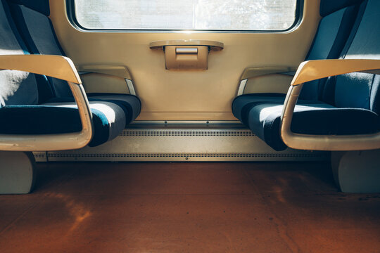 Symmetrical view of empty blue seats and a central window inside a clean passenger train compartment.
