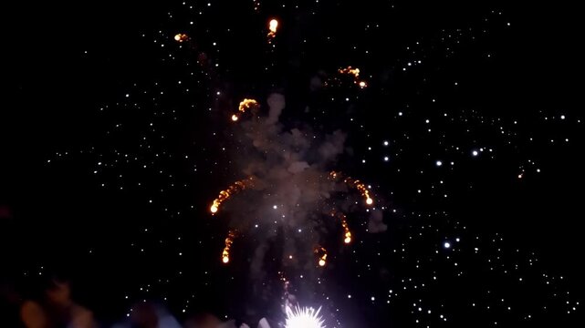 Golden and white fireworks burst outward and fade into sparkling trails against a dark night sky in a dramatic closeup display