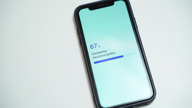 Smartphone on white table with insurance quote comparison stuck at 70 percent. Loading progress bar frozen on mobile screen