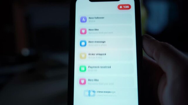 Smartphone screen with notification list and red counter badge in dark room. Incoming alerts stacking on mobile display