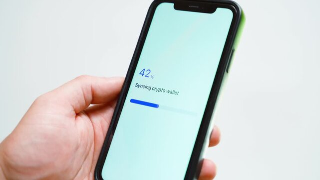 Hand holding smartphone with crypto wallet syncing stuck at 70 percent. Loading progress bar frozen on mobile screen