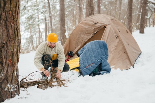 Man preparing campfire while winter camping alone