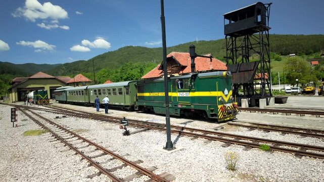 Green Yellow Locomotive Pulling Passenger Cars at Mountain Station