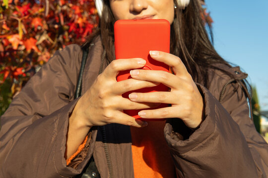 Woman holding smartphone outdoors listening to music in autumn