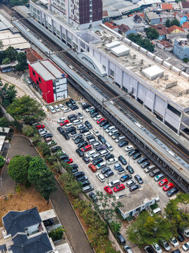 Aerial view of Stasiun Rawa Buntu featuring a crowded parking lot, railway tracks, and surrounding urban buildings in Kecamatan Serpong, Banten, Indonesia.