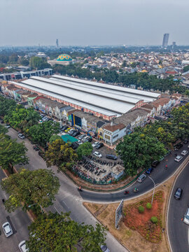 Aerial view of Pasar Modern BSD City featuring its large white roof, surrounding commercial buildings, parking areas, and nearby roads in Kecamatan Serpong, Banten, Indonesia.