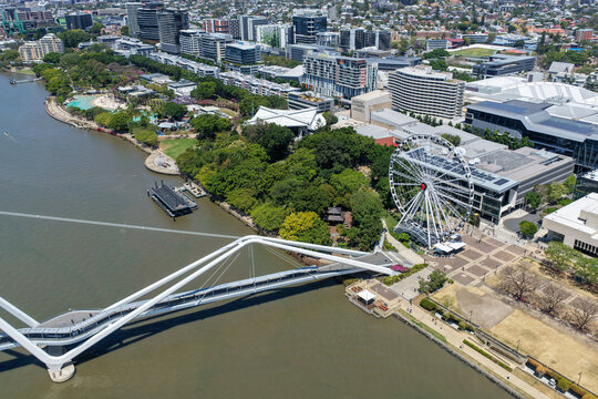 Aerial view of the Wheel of Brisbane, Neville Bonner Bridge, and Brisbane River flowing past South Bank Parklands and Streets Beach in Brisbane, Queensland, Australia.