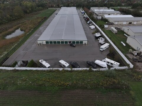 Aerial view of a long storage facility with rows of parking spaces occupied by recreational vehicles, boats, and trailers, situated in a suburban area, Mason, OH, United States.