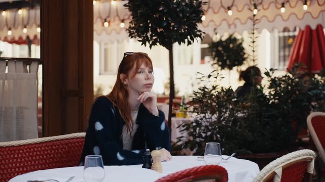 Young pensive woman waiting alone at a french restaurant
